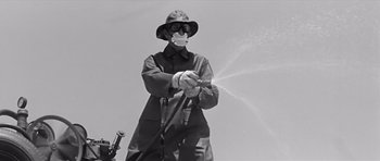 Movie still from “Hud” (1963), directed by Martin Ritt – A man spraying water from a garden hose on a sunny day; Medium shot, Low angle