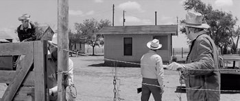 Movie still from “Hud” (1963), directed by Martin Ritt – A man in a cowboy hat standing in front of a fence; Wide shot, Over the shoulder angle