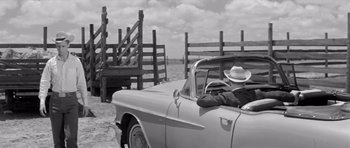 Movie still from “Hud” (1963), directed by Martin Ritt – An old photo of a man in a hat driving a car; Wide shot, Over the shoulder angle