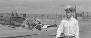 Movie still from “Hud” (1963), directed by Martin Ritt – A man in a cowboy hat sitting in the drivers seat of a car; Medium shot, Over the shoulder angle