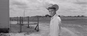 Movie still from “Hud” (1963), directed by Martin Ritt – A man in a cowboy hat standing next to a barbed wire fence; Medium shot, Low angle