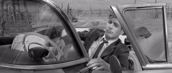 Movie still from “Hud” (1963), directed by Martin Ritt – A black and white photo of a man in a suit driving a car; Medium shot, Low angle