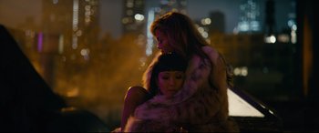 Movie still from “Hustlers” (2019), directed by Lorene Scafaria – Two women in fur coats embracing each other in the dark; Medium shot, High angle