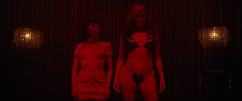 Movie still from “Hustlers” (2019), directed by Lorene Scafaria – Two women standing next to each other in a red room; Medium shot, Low angle
