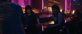 Movie still from “Hustlers” (2019), directed by Lorene Scafaria – Two women are sitting at a bar talking to each other; Medium shot, Over the shoulder angle