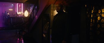 Movie still from “Hustlers” (2019), directed by Lorene Scafaria – A man standing in a dark room next to an atm machine; Medium shot, Low angle