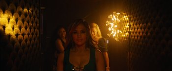 Movie still from “Hustlers” (2019), directed by Lorene Scafaria – A woman standing in front of two other women in a dark room; Medium shot, Over the shoulder angle