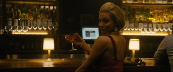 Movie still from “Hustlers” (2019), directed by Lorene Scafaria – A woman sitting at a table holding a glass of wine; Close Up shot, Over the shoulder angle