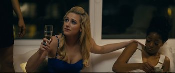 Movie still from “Hustlers” (2019), directed by Lorene Scafaria – A beautiful young lady holding a glass of wine; Close Up shot, Over the shoulder angle