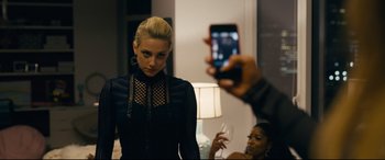 Movie still from “Hustlers” (2019), directed by Lorene Scafaria – A person taking a picture of a woman in a black dress; Medium shot, Over the shoulder angle