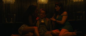Movie still from “Hustlers” (2019), directed by Lorene Scafaria – A man sitting between two women in a dark room; Medium shot, Low angle