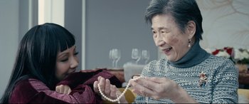 Movie still from “Hustlers” (2019), directed by Lorene Scafaria – An older man holding a string of pearls while a younger woman looks on; Close Up shot, Over the shoulder angle