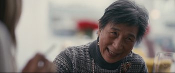 Movie still from “Hustlers” (2019), directed by Lorene Scafaria – An older woman wearing a sweater smiling for the camera; Close Up shot, Over the shoulder angle