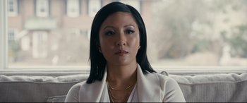 Movie still from “Hustlers” (2019), directed by Lorene Scafaria – A person sitting in a chair wearing a white jacket; Close Up shot, Over the shoulder angle