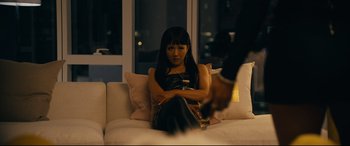 Movie still from “Hustlers” (2019), directed by Lorene Scafaria – A woman sitting on top of a white couch in a room; Medium shot, Over the shoulder angle