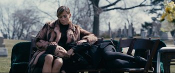 Movie still from “Hustlers” (2019), directed by Lorene Scafaria – Two women sitting on a park bench wearing fur coats; Medium shot, High angle