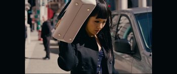 Movie still from “Hustlers” (2019), directed by Lorene Scafaria – A young woman holding onto a bag on her head; Medium shot, High angle
