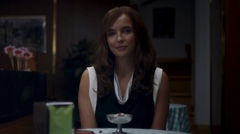 Movie still from “Killing Eve” (2018), created by Phoebe Waller-Bridge – A woman sitting at a table with a wine glass in front of her; Close Up shot, Over the shoulder angle