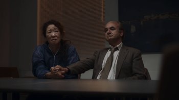 Movie still from “Killing Eve” (2018), created by Phoebe Waller-Bridge – A man and a woman sitting in front of a table; Medium shot, High angle