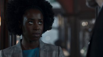 Movie still from “Killing Eve” (2018), created by Phoebe Waller-Bridge – A person with a black afro is looking at the camera; Close Up shot, Over the shoulder angle