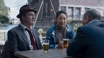 Movie still from “Killing Eve” (2018), created by Phoebe Waller-Bridge – A man and a woman sitting at a table with two beers; Medium shot, Over the shoulder angle