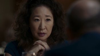Movie still from “Killing Eve” (2018), created by Phoebe Waller-Bridge – An older asian woman sitting in front of a man; Close Up shot, Over the shoulder angle