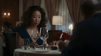 Movie still from “Killing Eve” (2018), created by Phoebe Waller-Bridge – A woman sitting at a table with a glass of wine in front of her; Close Up shot, Over the shoulder angle