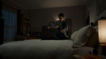 Movie still from “Killing Eve” (2018), created by Phoebe Waller-Bridge – A person sitting on a bed in a room; Wide shot, Low angle