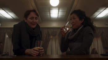 Movie still from “Killing Eve” (2018), created by Phoebe Waller-Bridge – Two women sitting at a table with a glass of orange juice; Medium shot, Over the shoulder angle