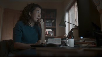 Movie still from “Killing Eve” (2018), created by Phoebe Waller-Bridge – A woman sitting in front of a computer at a desk; Close Up shot, High angle