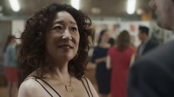Movie still from “Killing Eve” (2018), created by Phoebe Waller-Bridge – An older woman is smiling for the camera; Close Up shot, Over the shoulder angle