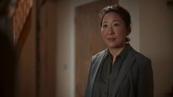 Movie still from “Killing Eve” (2018), created by Phoebe Waller-Bridge – A woman standing in front of a wooden door; Close Up shot, Over the shoulder angle