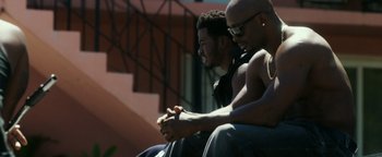 Movie still from “War Dogs” (2016), directed by Todd Phillips – A couple of men sitting next to each other on some steps; Medium shot, Over the shoulder angle