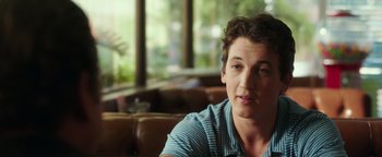 Movie still from “War Dogs” (2016), directed by Todd Phillips – A young man sitting on a couch in a living room; Close Up shot, Over the shoulder angle
