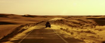 Movie still from “War Dogs” (2016), directed by Todd Phillips – A man riding a vehicle down a road in the desert; Extreme Wide shot, High angle