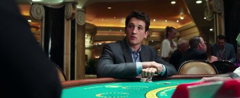 Movie still from “War Dogs” (2016), directed by Todd Phillips – A man sitting at a table in front of cards; Medium shot, Over the shoulder angle