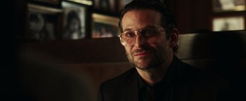 Movie still from “War Dogs” (2016), directed by Todd Phillips – A person wearing glasses and a suit; Close Up shot, Over the shoulder angle