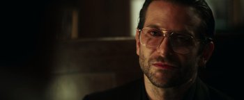 Movie still from “War Dogs” (2016), directed by Todd Phillips – A person wearing glasses and a suit; Close Up shot, Over the shoulder angle