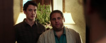 Movie still from “War Dogs” (2016), directed by Todd Phillips – Two men standing next to each other in front of a plant; Medium shot, Low angle