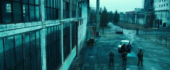 Movie still from “War Dogs” (2016), directed by Todd Phillips – A man standing on a sidewalk near a building; Extreme Wide shot, High angle
