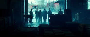 Movie still from “War Dogs” (2016), directed by Todd Phillips – A group of people standing in a room; Wide shot, High angle