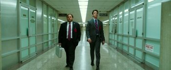 Movie still from “War Dogs” (2016), directed by Todd Phillips – A couple of men in suits walking down a hall way; Medium shot, Low angle