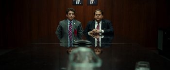 Movie still from “War Dogs” (2016), directed by Todd Phillips – Two men in suits sitting at a conference room table; Medium shot, Low angle