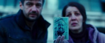 Movie still from “War Dogs” (2016), directed by Todd Phillips – A man and a woman holding up an old photo; Extreme Close Up shot, Over the shoulder angle