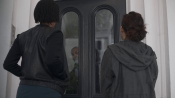 Movie still from “Killing Eve” (2018), created by Phoebe Waller-Bridge – Two people standing in front of an open door; Medium shot, Over the shoulder angle
