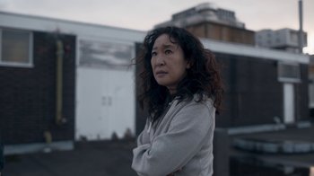 Movie still from “Killing Eve” (2018), created by Phoebe Waller-Bridge – A woman standing in front of a building with her arms crossed; Close Up shot, Over the shoulder angle