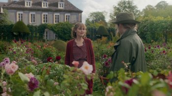 Movie still from “Killing Eve” (2018), created by Phoebe Waller-Bridge – A woman in a red dress talking to a man in a green hat; Medium shot, Over the shoulder angle