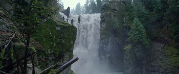 Movie still from “War for the Planet of the Apes” (2017), directed by Matt Reeves – A group of people standing on top of a waterfall near trees; Extreme Wide shot, Low angle