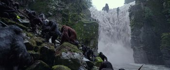 Movie still from “War for the Planet of the Apes” (2017), directed by Matt Reeves – A group of monkeys standing on rocks near a body of water; Extreme Wide shot, Low angle