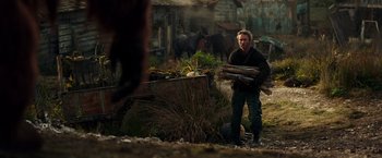 Movie still from “War for the Planet of the Apes” (2017), directed by Matt Reeves – A man holding a bunch of wood in his hands; Medium shot, Over the shoulder angle